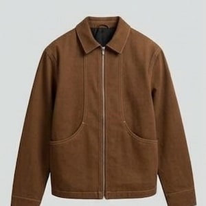May include: A brown jacket featuring a full-length silver-tone front zipper, a classic fold-down collar, and two large curved front pockets. The garment has long sleeves with cuffs and a black interior lining visible at the neckline.