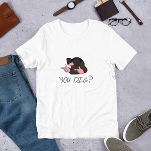 Op de afbeelding: Wit T-shirt met een cartoonmol die een zonnebril draagt en met beide handen wijst. De tekst "YOU DIG?" is onder de mol gedrukt.
