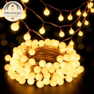 Op de afbeelding: Een lichtsnoer met warmwitte LED-bolletjes, bestaande uit kleine, ronde lampjes bevestigd aan een dunne, flexibele koperdraad. De lampjes zijn opgerold tot een dichte, cirkelvormige kluwen, met extra strengen die erboven hangen.