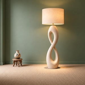 May include: A floor lamp with a beige, textured, infinity-shaped base and a cylindrical fabric shade. Beside it sits a small, round wooden stool holding a decorative ceramic vase with brown and black painted patterns.