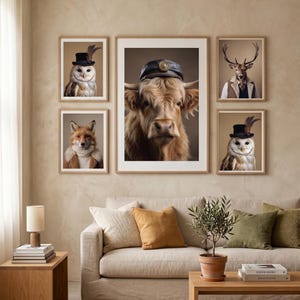 Puede incluir: Una pared de galería con cinco láminas enmarcadas de animales antropomórficos. La impresión central grande muestra una vaca de las Tierras Altas con una gorra azul marino, flanqueada por dos búhos con chistera, un zorro con chaleco y un ciervo con traje.