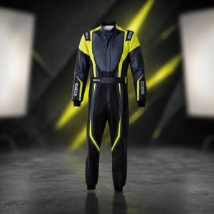 May include: A full-body racing suit in black, dark gray, and bright yellow. The suit features a high collar, long sleeves with black cuffs, and the Sparco brand name printed in white on the chest, belt, and sleeves. The design includes yellow accents.