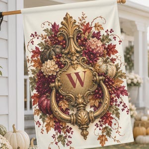 May include: A rectangular garden flag featuring a central ornate gold door knocker design with the letter W in deep red. The design is surrounded by a vibrant autumn arrangement of pumpkins, red berries, and fall-coloured leaves on a cream background.