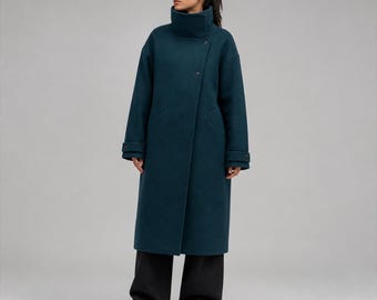 May include: A long, dark teal coat featuring a high, structured funnel neck collar, an asymmetrical front closure with visible buttons, long sleeves with buttoned cuffs, and a straight, knee-length silhouette paired with wide-leg black trousers.