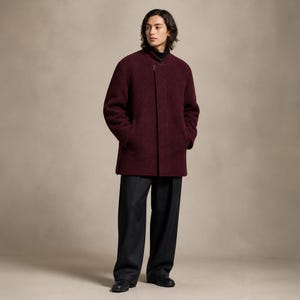 May include: A deep burgundy wool-blend coat featuring a high stand-up collar, a concealed front zipper closure, and long sleeves. The coat is paired with dark charcoal gray wide-leg trousers and black leather shoes, creating a structured ensemble.