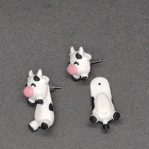 Adorable 3D-printed cow jumper earrings featuring playful black-and-white cows with sweet pink noses—perfect for adding a fun, quirky touch