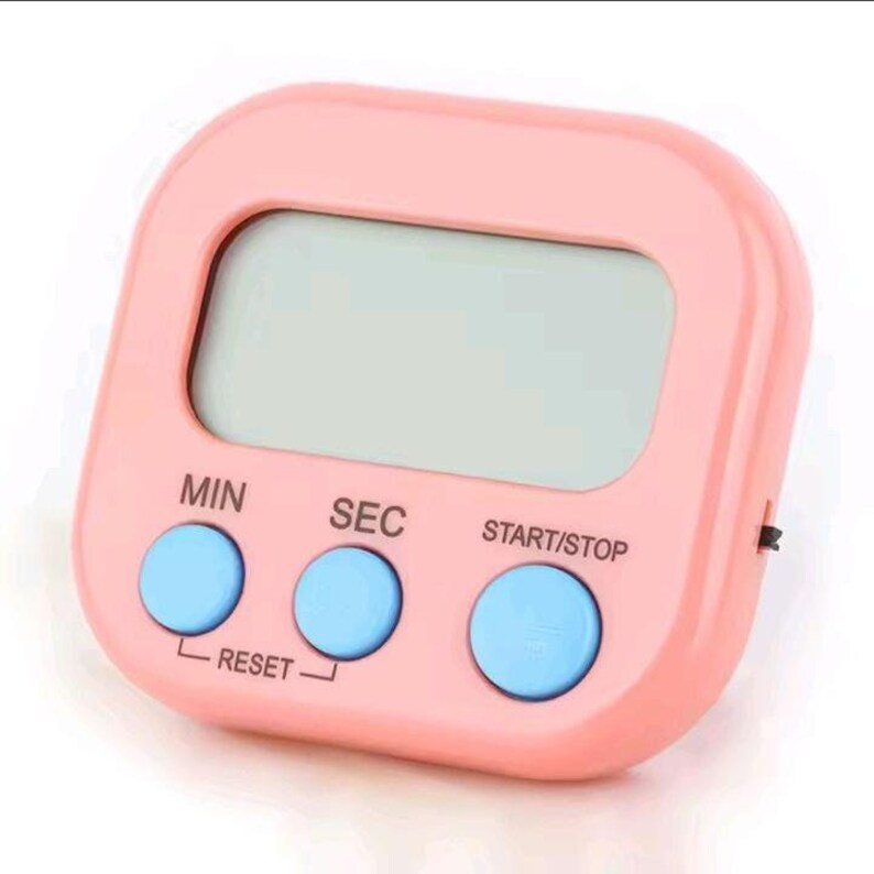 May include: A square-shaped digital kitchen timer with a light pink plastic casing and a central LCD screen. It features three round, light blue buttons labeled MIN, SEC, and START/STOP, with the word RESET printed below the first two buttons.