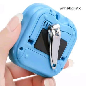 May include: A square, light blue digital timer featuring a black magnetic panel on the back and a silver metal clip attached to the center. The text "with Magnetic" is printed in black in the upper right corner of the device casing.