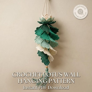 Puede incluir: Un colgante de pared de loto hecho a ganchillo con una flor de loto color crema en la parte superior, seguido de hojas en cascada en tonos verde oscuro, verde medio y crema. Termina con una borla y una cuenta de madera. Texto: CROCHET LOTUS WALL HANGING PATTERN.