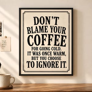 May include: A rectangular framed wall art piece with a cream background and black text that reads: DON'T BLAME YOUR COFFEE FOR GOING COLD. IT WAS ONCE WARM, BUT YOU CHOOSE TO IGNORE IT. The frame is thin and black, featuring a decorative border design.