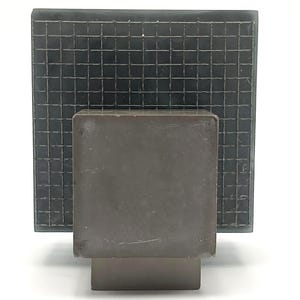 May include: A square, dark gray, solid block base supports a larger, square, dark gray panel featuring a prominent, raised, grid-like wire mesh pattern across its entire surface. The object is composed of a matte, uniform, dark gray material.