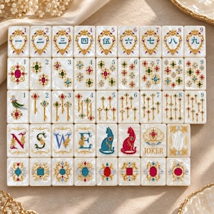 May include: A set of rectangular mahjong tiles with a pearlescent white finish. The tiles feature intricate gold filigree frames, colorful gemstone illustrations, ornate keys, the letters N, S, W, E, cat silhouettes, and a Joker tile.