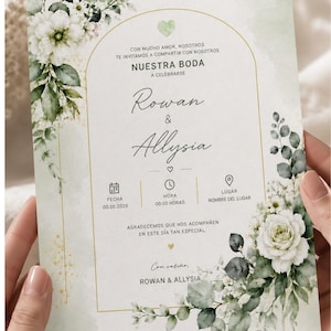 May include: A rectangular wedding invitation card featuring a gold arched frame, watercolor white roses, and green eucalyptus leaves. The text reads: CON MUCHO AMOR, NOSOTROS TE INVITAMOS A COMPARTIR CON NOSOTROS NUESTRA BODA, Rowan & Allysia.
