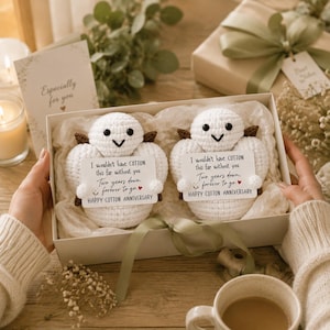 May include: Two white crocheted cotton figures with black eyes and brown accents, nestled in a gift box. Each holds a card reading: I wouldn't have COTTON this far without you. Two years down, forever to go. HAPPY COTTON ANNIVERSARY.