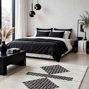 Pode incluir: Um tapete retangular com base branca e um padr&atilde;o geom&eacute;trico preto composto por duas formas de diamante ligadas por uma barra horizontal. O texto Ahad global rugs aparece nos cantos superior direito e inferior esquerdo da imagem.