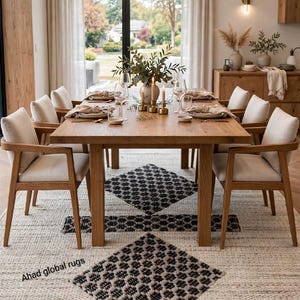 Pode incluir: Um tapete retangular com uma base de cor creme e um padr&atilde;o geom&eacute;trico repetitivo de diamantes em preto e cinzento. O texto Ahad global rugs est&aacute; impresso no canto inferior esquerdo do tapete, colocado sob uma mesa de jantar de madeira.