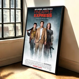 May include: A framed film poster for Pineapple Express featuring Seth Rogen and James Franco. The poster displays the film title in red text, the tagline Put this in your pipe and smoke it, and the release date of August 2008 in a black frame.
