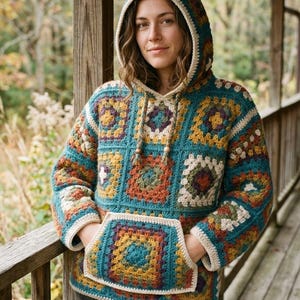 Peut inclure: Un pull à capuche à manches longues composé de carrés de crochet aux tons bleu sarcelle, jaune moutarde, orange rouille et crème. Le vêtement présente une poche kangourou à l'avant, une capuche à bordure crème et deux cordons tressés.