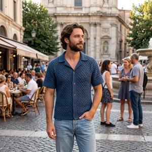 May include: A short-sleeved, navy blue button-down shirt featuring a textured, open-knit crochet pattern with a classic collar. The shirt is paired with light blue denim jeans, creating a casual look suitable for a public outdoor setting.