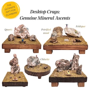 Pode incluir: Cinco plataformas de madeira com dioramas em miniatura de formações rochosas rotuladas como Quartz, Petrified wood, Feldspar e Chlorite. Cada display inclui pequenas figuras de escaladores e o texto Desktop Crags: Genuine Mineral Ascents.