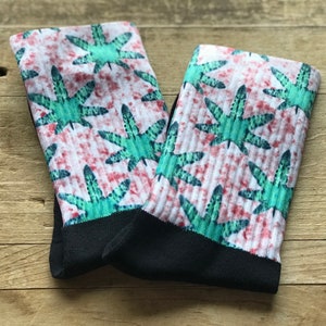 May include: A pair of white socks with a green and red leaf pattern. The socks have a black cuff.
