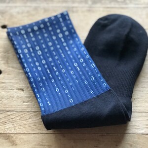 K&ouml;nnte beinhalten: Ein Paar blaue Socken mit einem wei&szlig;en Bin&auml;rcode-Muster. Die Socken haben einen schwarzen Bund.