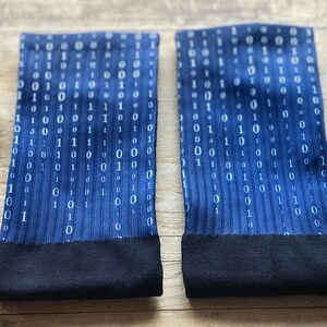 K&ouml;nnte beinhalten: Ein Paar blaue Socken mit einem wei&szlig;en Bin&auml;rcode-Muster. Die Socken haben einen schwarzen Bund.