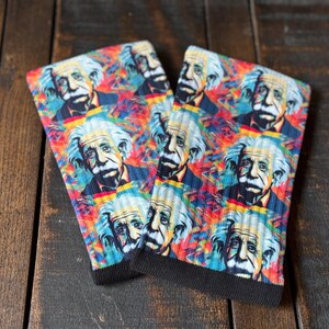 May include: A pair of colorful socks with a repeating pattern of Albert Einstein's face. The socks are a mix of bright colors, including red, blue, green, yellow, and orange. The background is a psychedelic swirl pattern.