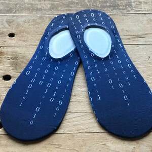 Puede incluir: Un par de calcetines invisibles azules con un patrón de código binario blanco. Los calcetines están hechos de un material suave y cómodo y son perfectos para el uso diario.