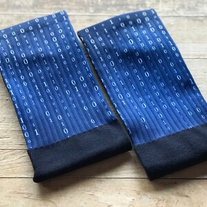 K&ouml;nnte beinhalten: Ein Paar blaue Socken mit einem wei&szlig;en Bin&auml;rcode-Muster. Die Socken haben einen schwarzen Bund.