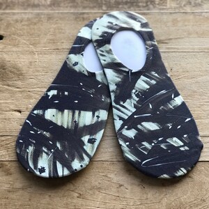 Puede incluir: Un par de calcetines invisibles negros y blancos con un patrón abstracto de pinceladas.