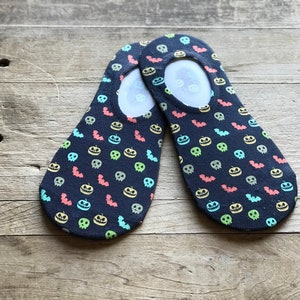May include: A pair of black no-show socks with a Halloween-themed print featuring colourful pumpkins, bats, and skulls.