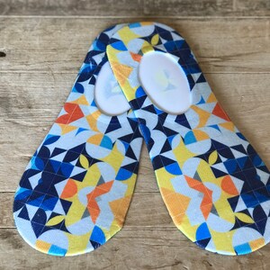 May include: A pair of no-show socks with a geometric pattern in shades of blue, yellow, and orange. The socks have a white background and are made of a soft, breathable fabric.