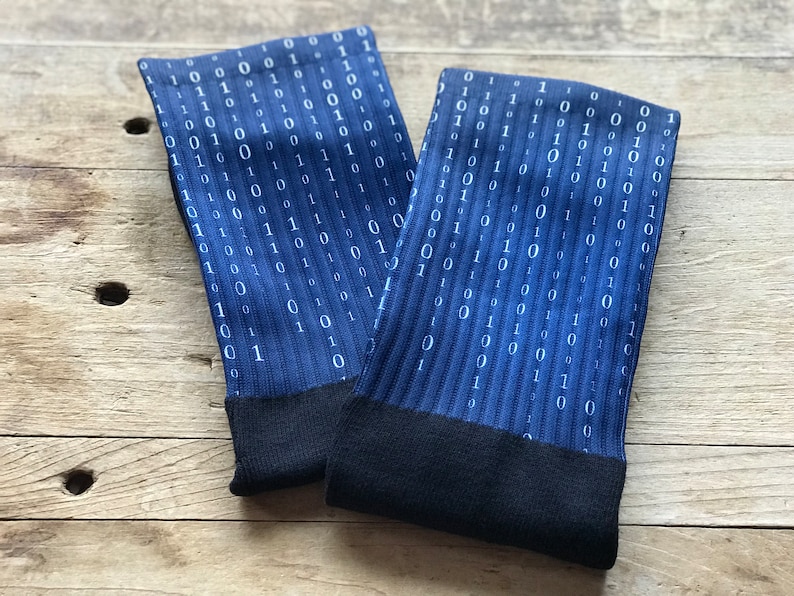 K&ouml;nnte beinhalten: Ein Paar blaue Socken mit einem wei&szlig;en Bin&auml;rcode-Muster. Die Socken haben schwarze B&uuml;ndchen.