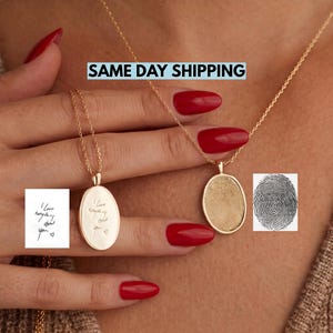 Puede incluir: Dos collares con colgantes ovalados dorados en cadenas delicadas. Un colgante presenta una huella dactilar grabada, mientras que el otro muestra el texto en cursiva 'I love everything about you' con un pequeño corazón, igual a las imágenes de referencia.