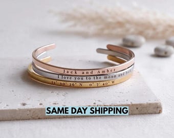 Può includere: Tre bracciali rigidi in metallo impilati nei toni dell'oro rosa, argento e oro. Il bracciale in oro rosa è inciso con Jack and Amber, quello in argento con I love you to the moon and back e quello in oro con 51 30 26 N 0 7 40 W.