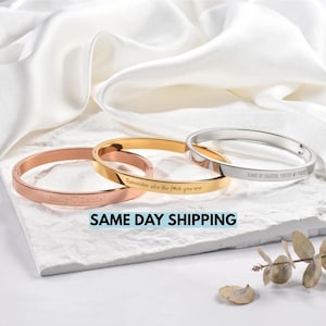 Può includere: Tre bracciali rigidi in metallo nei toni dell'oro rosa, oro e argento. Il bracciale in oro rosa è inciso con "Emily ♡ Daniel", quello in oro con "Remember who the f*ck you are" e quello in argento con "ALWAYS MY DAUGHTER, FOREVER MY FRIEND".