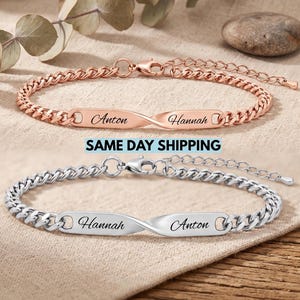 Op de afbeelding: Twee gourmetkettingarmbanden met een centrale gedraaide metalen staaf. De ene armband is roségoudkleurig met de namen Anton en Hannah gegraveerd. De andere is zilverkleurig met de namen Hannah en Anton gegraveerd. Beide hebben een karabijnsluiting.
