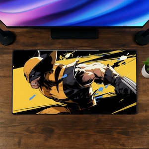 May include: A rectangular desk mat featuring a graphic illustration of the character Wolverine in a dynamic pose. The character wears a yellow and black suit with metallic claws extended. The background consists of bold yellow and black diagonal stripes.