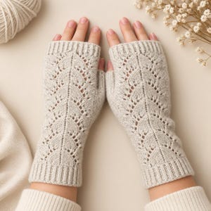 May include: A pair of light beige fingerless gloves featuring a delicate vertical lace pattern with openwork details. The gloves have ribbed cuffs at the top and bottom, extending from the knuckles to the mid-forearm, crafted in a soft knit texture.