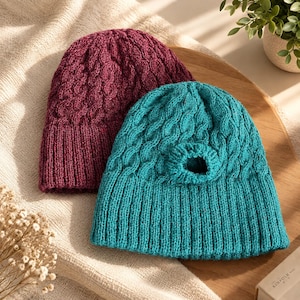 May include: Two knitted beanies, one in deep burgundy and one in teal blue. Both hats feature a textured cable knit pattern on the crown and a ribbed knit cuff at the base. The teal beanie includes a circular opening near the top of the crown.