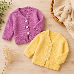 May include: Two long-sleeve knit cardigans, one in bright purple and one in soft yellow. Each cardigan features a V-neckline, three round white buttons down the front, and a textured garter stitch pattern along the hem and sleeve cuffs.