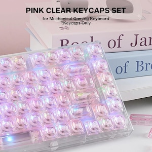 Peut inclure: Un ensemble de touches transparentes roses pour clavier mécanique de jeu. Les touches sont translucides avec une teinte rose et comportent des lettres blanches. Le texte sur l'image indique : PINK CLEAR KEYCAPS SET for Mechanical Gaming Keyboard *Keycaps Only.