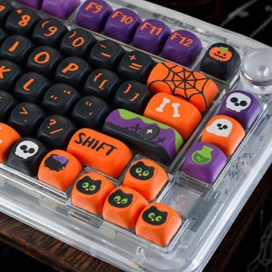 Op de afbeelding: Een mechanisch toetsenbord met aangepaste toetsen in een Halloween-thema. De set bevat zwarte toetsen met oranje letters, paarse functietoetsen en oranje toetsen versierd met iconen van schedels, spoken, katten, pompoenen en spinnenwebben.