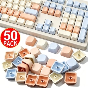 Puede incluir: Un paquete de 50 teclas de repuesto para teclado mecánico en tonos pastel crema, melocotón y azul claro. El conjunto incluye varias teclas cuadradas con parte superior cóncava y vástagos en forma de cruz en la parte inferior, junto a un teclado.