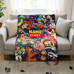 May include: A rectangular fleece blanket featuring a vibrant, multi-colored graphic print of various animated characters from the Toy Story franchise. The center includes the text NAME STORY and YOU'VE GOT A FRIEND IN ME against a dark blue background.