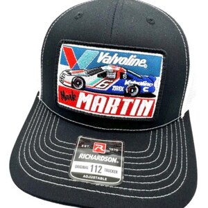 Puede incluir: Una gorra de camionero negra con un parche bordado rectangular de un coche de carreras Valvoline con el número 6 y el nombre Mark Martin. La gorra tiene costuras blancas en contraste en la visera y una pegatina Richardson 112 en el frente.