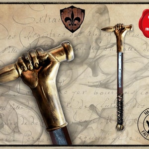 May include: A golden hand holding a dagger, mounted on a wooden staff with a metal band. The staff is wrapped in black leather and has a metal tip. The hand is holding the dagger in a threatening pose. The background is a vintage-style parchment with handwritten text.