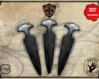 May include: Three black and silver daggers with a pointed tip and a rounded handle. The daggers are arranged in a triangular pattern on a background of old paper with writing.