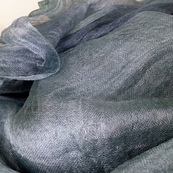 May include: A soft, sheer, gray fabric with a delicate texture. The fabric is draped and folded, creating a sense of movement and flow.